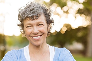 A smiling older woman in a bright outdoor setting