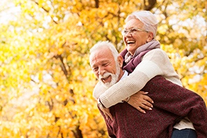 A laughing senior woman hugging an older man from behind